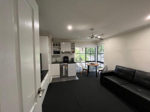 a living room with a black couch and a kitchen at 8 Heather in Belgrave South