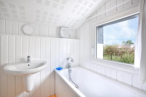 Un baño con lavabo, bañera y ventana. en La Villa du Pré Sec - Grande Plage à proximité, en Barneville-Carteret