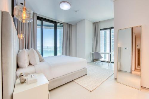 una camera bianca con un grande letto e finestre in vetro di Address JBR with Sea View & Maid Room - Mint Stay a Dubai