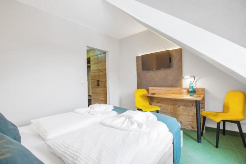 a bedroom with a bed and a desk with yellow chairs at Ferien Hotel Spreewald in Kolkwitz
