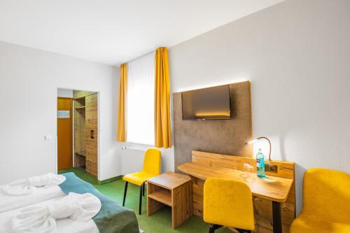 a hotel room with a table and yellow chairs at Ferien Hotel Spreewald in Kolkwitz