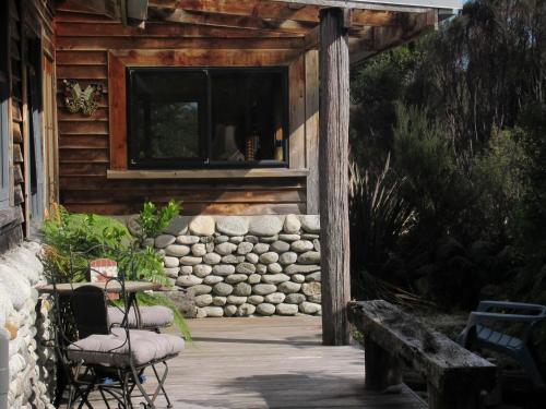 um alpendre de uma cabana de madeira com cadeiras e uma janela em Beaconstone Eco Stay - off grid retreat em Charleston