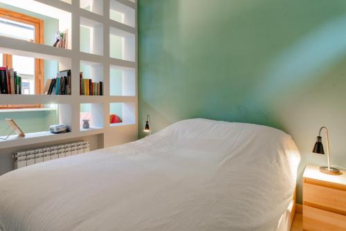 um quarto com uma cama branca e uma estante de livros em Ca' Sineo em Turim