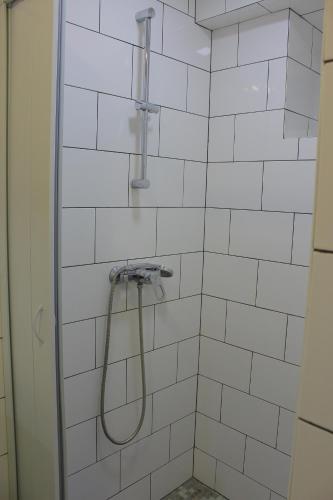 um chuveiro com uma mangueira numa casa de banho em azulejos brancos em Uneed Rooms Petropavlivska em Kiev