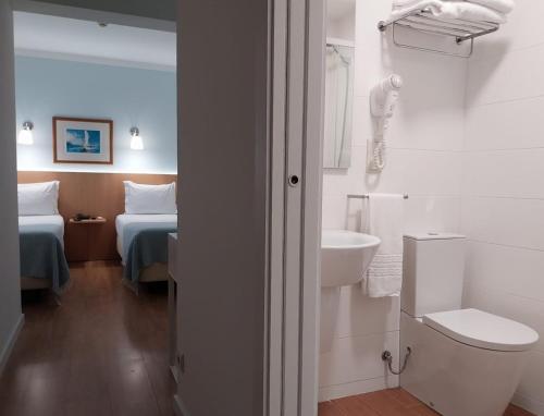 a bathroom with a toilet and a sink and a bed at Hotel Santiago in Ílhavo