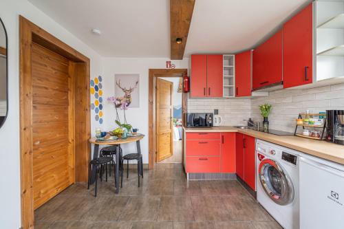 a kitchen with red cabinets and a table with chairs at 4 Bedroom House with Playground, BBQ & Free Parking in Rīga