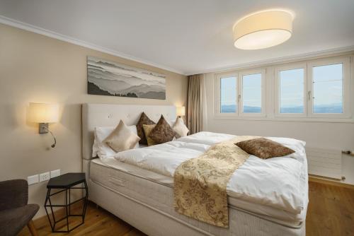 een slaapkamer met een groot bed met witte lakens en kussens bij Boutique Hotel Moosegg in Emmenmatt