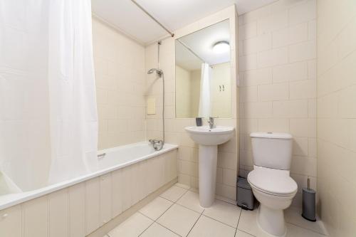 a bathroom with a toilet and a tub and a sink at The Stratford Apartments in London