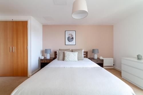 sypialnia z dużym białym łóżkiem i dwoma stołami w obiekcie The Stratford Apartments w Londynie