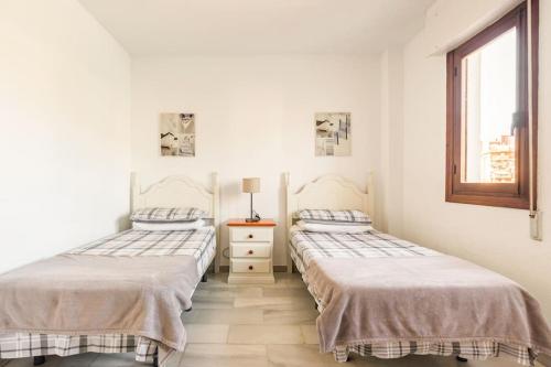 2 bedden in een witte kamer met een raam bij Beautiful 2 bed apartment located at Pueblo Evita in Benalmádena