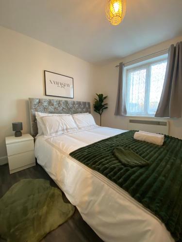 a bedroom with a large bed with a green blanket at Cosy Apartment Near Bluewater With Private Parking in Kent
