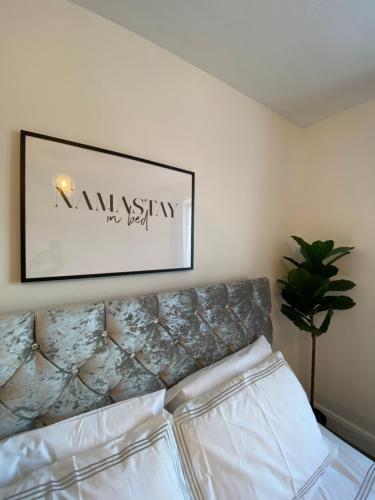 a bedroom with a bed with a picture on the wall at Cosy Apartment Near Bluewater With Private Parking in Kent