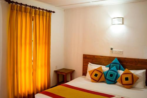 Wild Hut Habarana في هارابانا: غرفة نوم بسرير وستارة برتقال