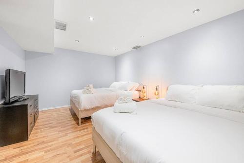 a bedroom with two beds and a flat screen tv at Large Townhome Near Anthony Henday in Ellerslie with Driveway & Visitor Parking, King Bed, 4 Queen Beds, Fully Equipped Kitchen & More! in Edmonton