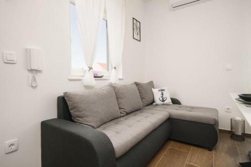 a couch sitting in a living room with a window at Apartment Stefanio in Vodice
