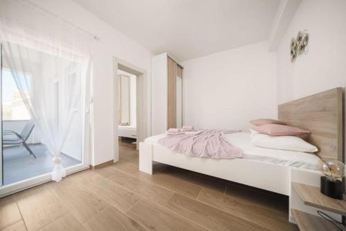 a white bedroom with a bed and a large window at Apartment Stefanio in Vodice
