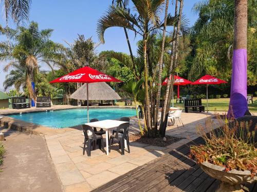a pool with a table and chairs and umbrellas at Nabana Lodge in Hazyview