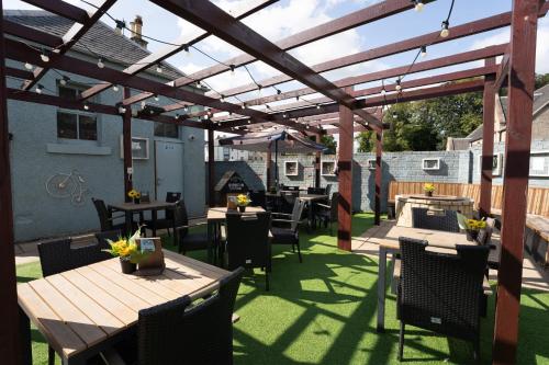 a patio with tables and chairs under a wooden pergola at West Port Hotel in Linlithgow