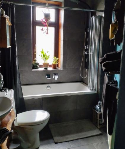 a bathroom with a tub and a toilet and a window at Large double room in Glasgow