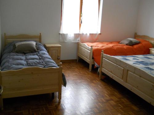a bedroom with two beds and a window at Baita Figliezzi in Castello Tesino