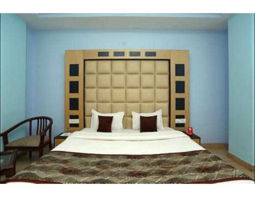 a bedroom with a large bed with a large headboard at Hotel Kolam, Dehradun in Dehradun