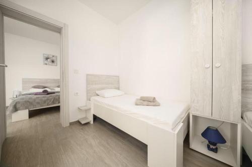 a white bedroom with a bed and a mirror at Apartment Stefanio in Vodice
