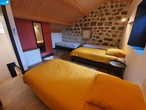 1 Schlafzimmer mit 2 Betten und einer Steinmauer in der Unterkunft Romanélou in Balazuc
