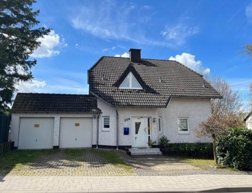 a white house with a black roof and two garage at Gartenparadies mit Rheinblick in Urbar in Urbar-Mayen-Koblenz
