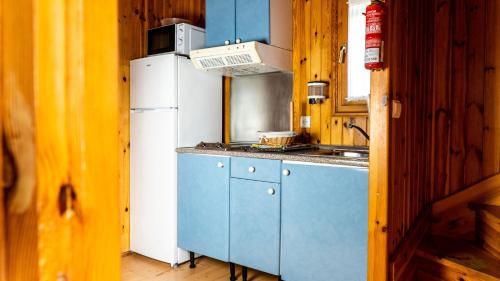 uma cozinha com armários azuis e um frigorífico branco em Camping Playa Las Dunas em El Puerto de Santa María