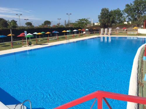 a large blue swimming pool with umbrellas at Camping Playa Las Dunas in El Puerto de Santa María