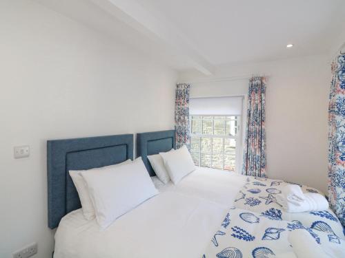 a bedroom with a white bed and a window at Quay Cottage in Salcombe