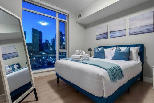 a bedroom with a large bed with a large window at Downtown Luxurious Apartment with Parking and Gym in Calgary