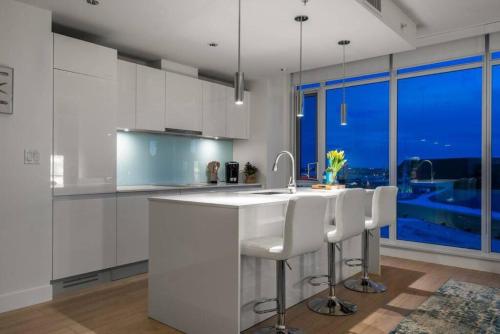 a kitchen with white cabinets and a sink and a window at Downtown Luxurious Apartment with Parking and Gym in Calgary