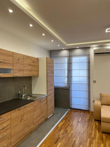 cocina con armarios de madera, fregadero y sofá en Lux Apartman Inđija, en Inđija