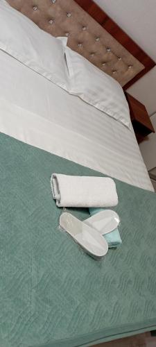 a bed with a towel and a pair of slippers at ЖК Молодежный in Almaty