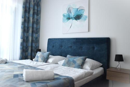 a bedroom with a bed with a blue headboard at Tabáň Halifax apartment - city center & free parking in Nitra
