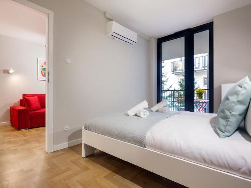 a bedroom with a bed and a window and a red chair at Tyzenhauz Apartments Vistula with Parking in Krakow