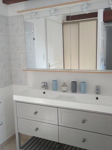 une salle de bain avec un lavabo blanc et un miroir dans l'établissement Les Trois Geais, aux Épesses