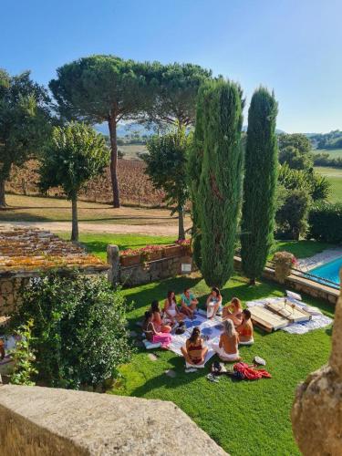 a group of people sitting on the grass near a pool at Villa Arzilla Antica Residenza di campagna in Vitorchiano