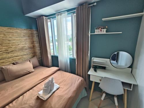 a bedroom with a bed and a desk and a mirror at Premiere Haven MOA Staycation in Manila