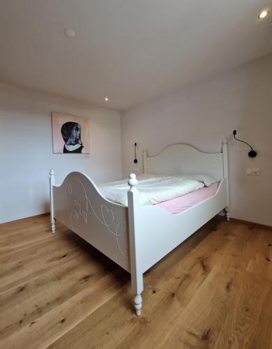 a white bed in a room with a wooden floor at Chasa Siringia in Samnaun