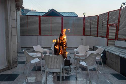 a fire pit in a courtyard with white chairs at Rock Castle By DLS Hotels in Shimla
