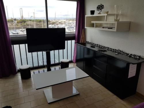 ein Wohnzimmer mit einem Schreibtisch und einem großen Fenster in der Unterkunft T3 70 m2 standing Cap d'Agde 4-6 pers in Cap d'Agde