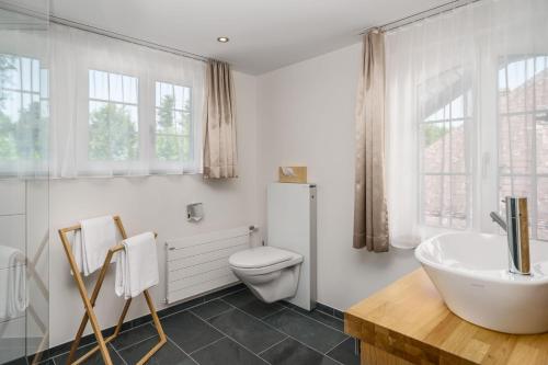 a white bathroom with a toilet and a sink at Boutique Hotel Moosegg in Emmenmatt