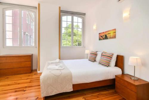 a bedroom with a white bed and two windows at Lightoasis Oeiras 1 in Oeiras