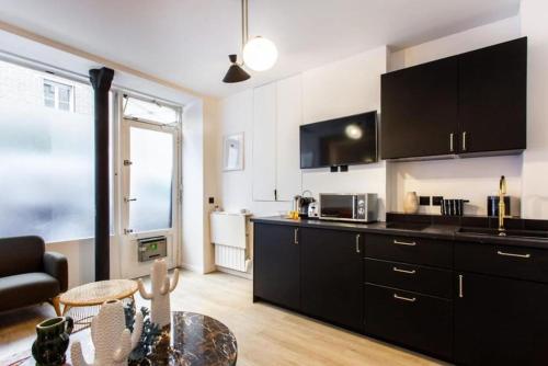 une cuisine avec des armoires noires et un salon dans l'établissement St Germain-Bon Marché - cosy n°2, à Paris