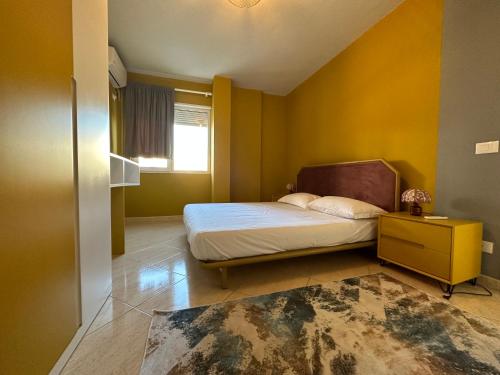 - une chambre avec un lit et un mur jaune dans l'établissement Joni's Condo at Mali i Robit, à Golem