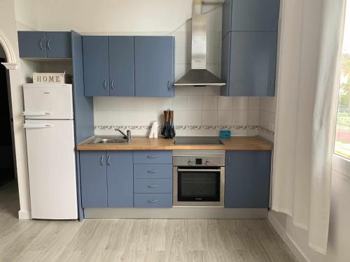 eine Küche mit blauen Schränken und einem weißen Kühlschrank in der Unterkunft Apartamento 8 mamia costa in Torreguadiaro