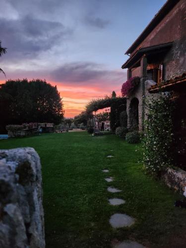a grass yard with a stone path next to a building at Villa Arzilla Antica Residenza di campagna in Vitorchiano