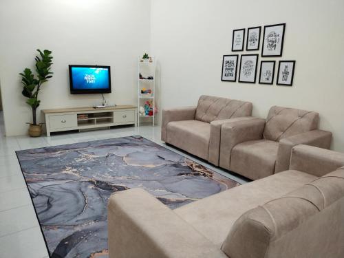 WAFID HOMESTAY 2 SERI ISKANDAR في سيري إسكندر: غرفة معيشة مع كنبتين وتلفزيون بشاشة مسطحة